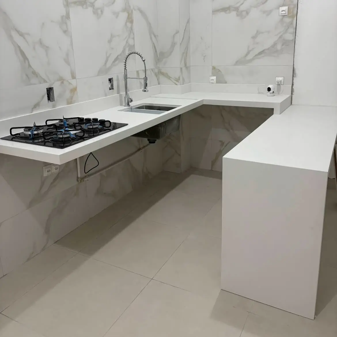 Cozinha em L com cooktop e bancada em pedra clara